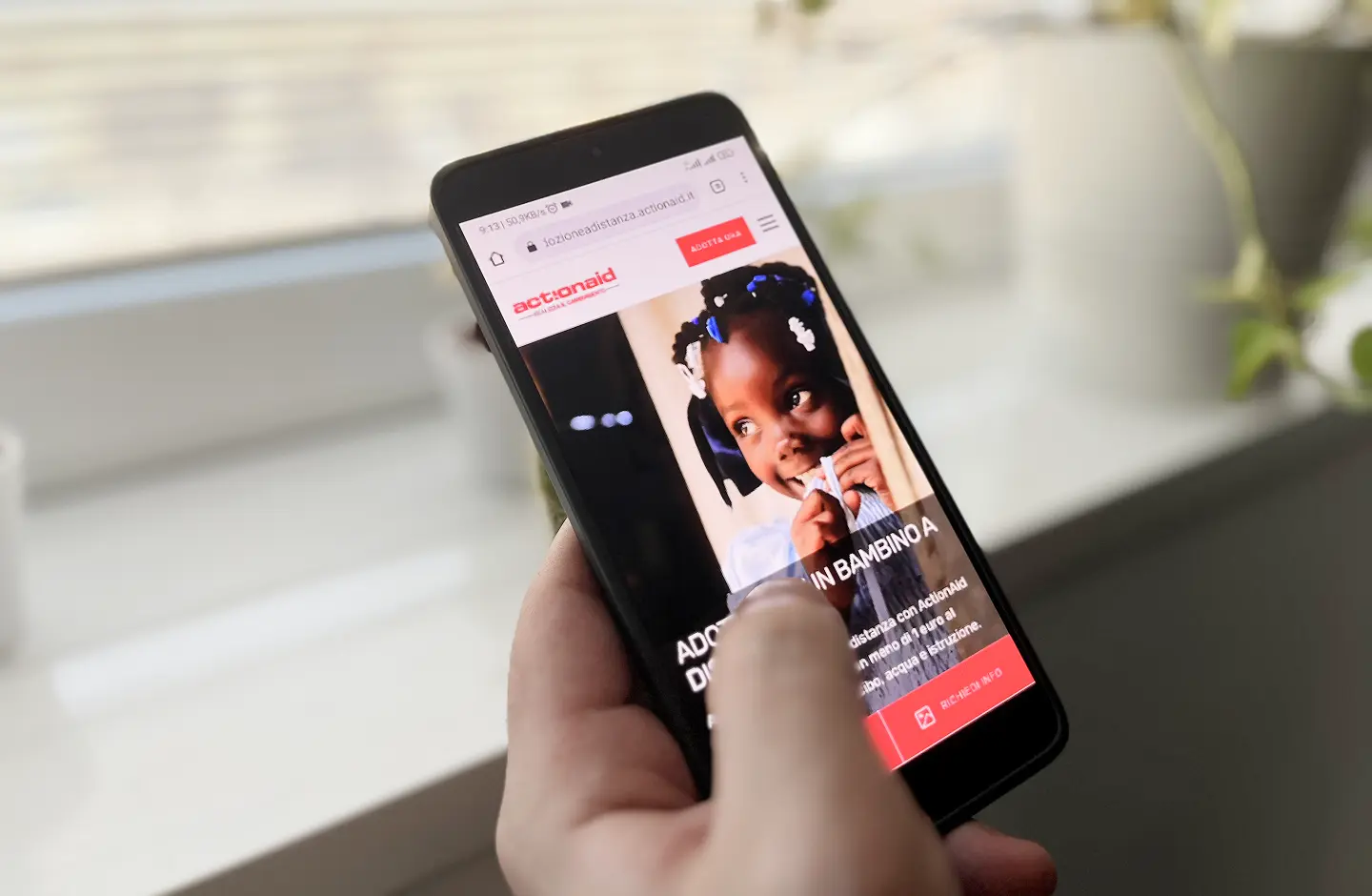 utente che effettua test di usabilità da mobile il sito actionaid che mostra il volto sorridente di una bambina africana